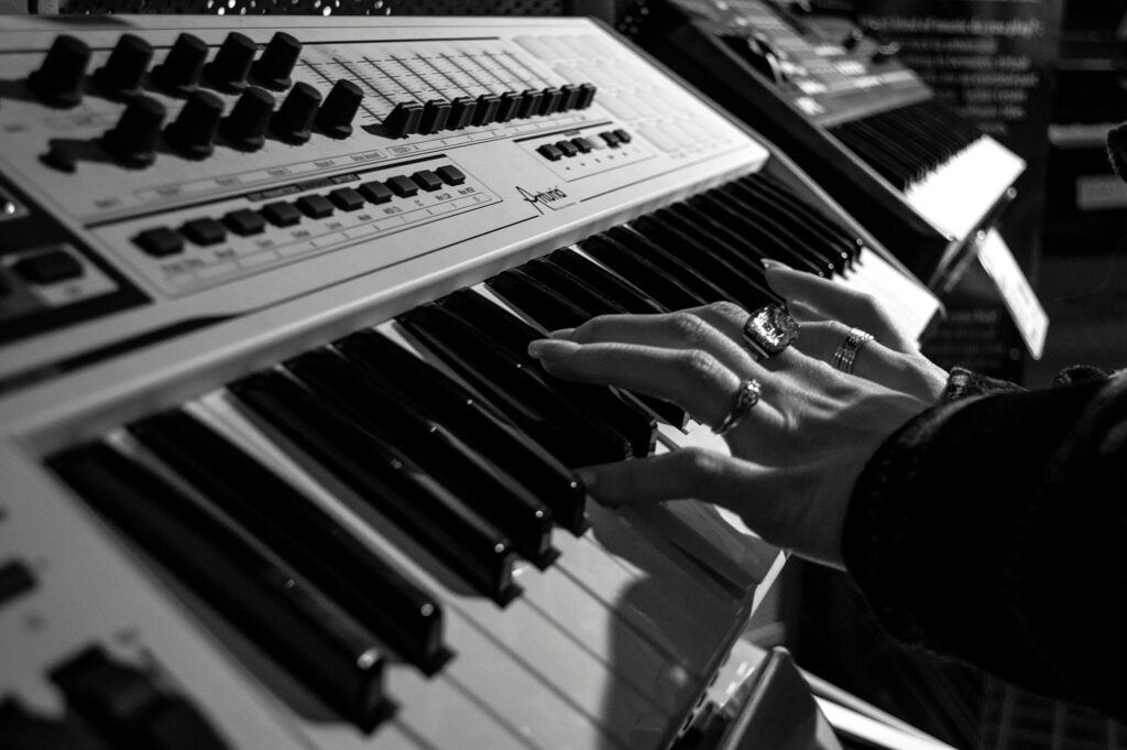 A musician's hand adorned with rings playing an electronic keyboard.